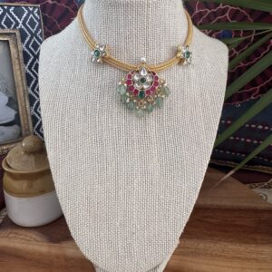 Jadau Kundan floral pendant necklace on a gold cord with ruby and emerald accents.