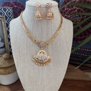 Traditional gold-toned Impon Attigai necklace set with white floral pendant and matching earrings.