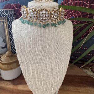 Gold-toned Kundan choker with soft emerald-green beads and matching earrings.