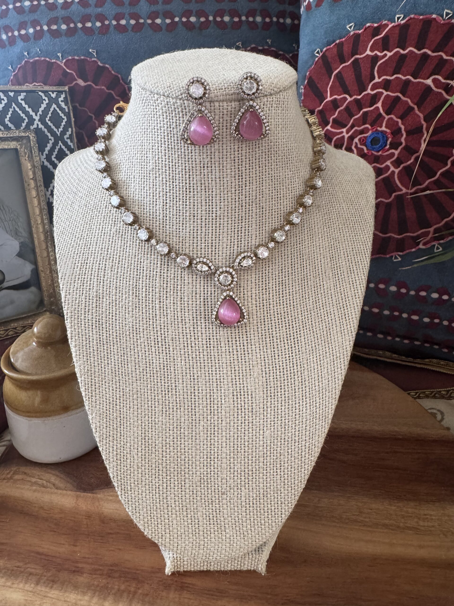 Gold-toned necklace with a pink and green Kundan pendant and pearl drops.