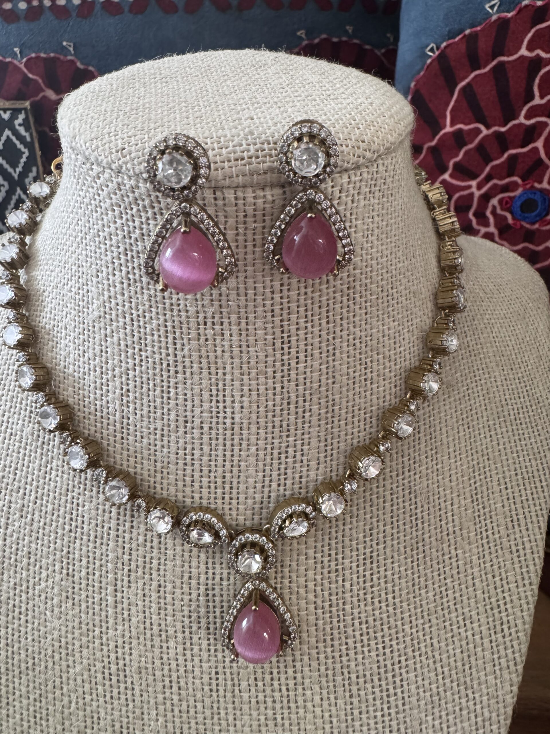 Gold-toned necklace with a pink and green Kundan pendant and pearl drops.