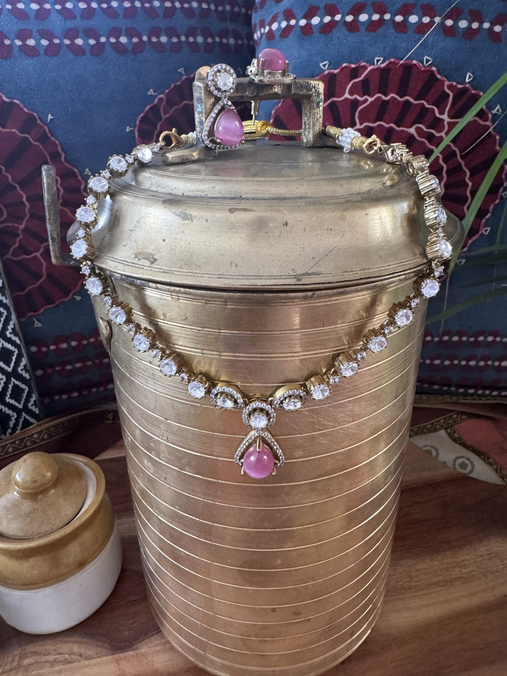 Gold-toned necklace with a pink and green Kundan pendant and pearl drops.