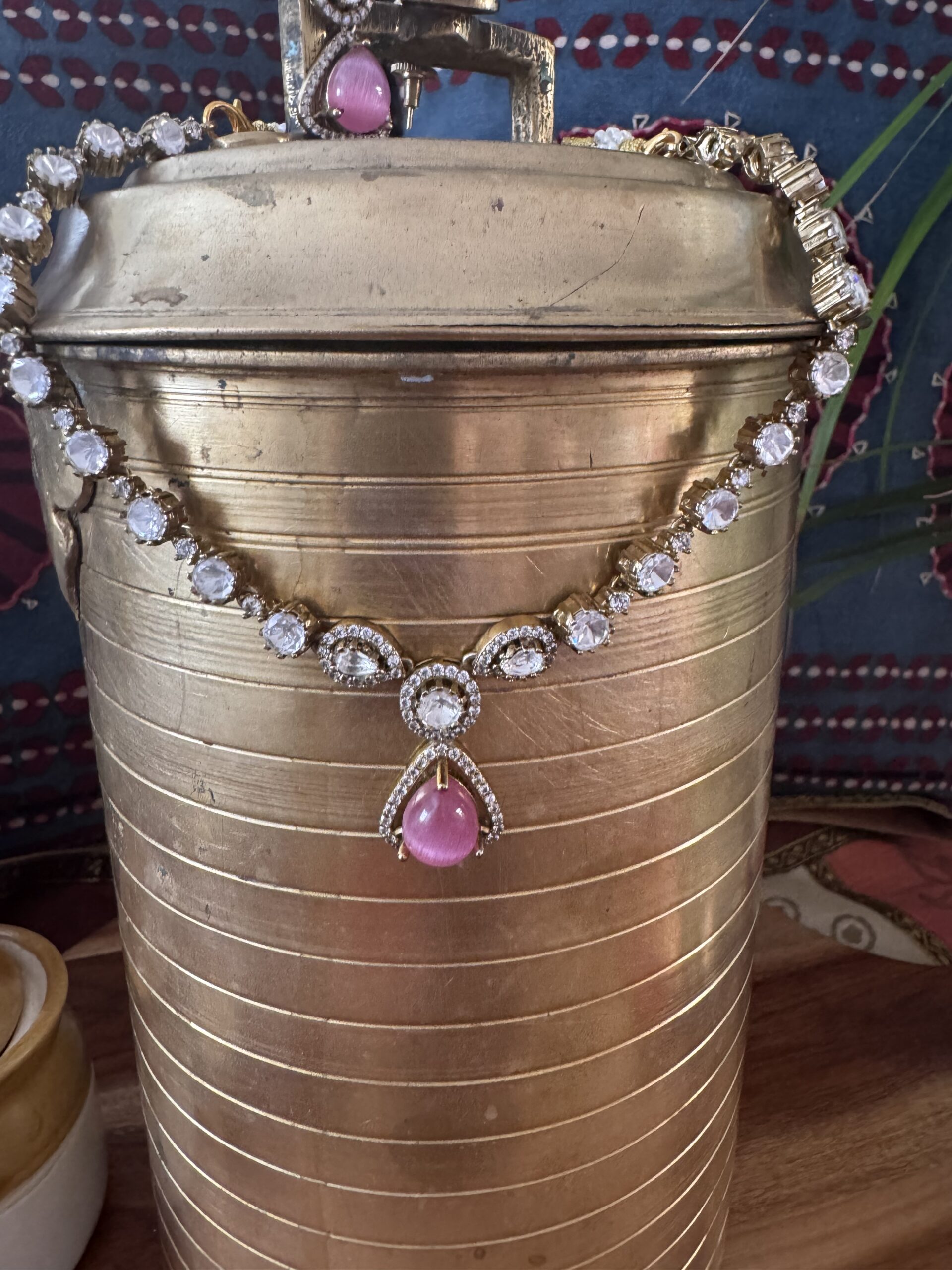 Gold-toned necklace with a pink and green Kundan pendant and pearl drops.