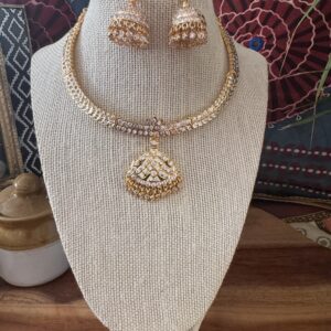 Gold-toned necklace with a pink and green Kundan pendant and pearl drops.