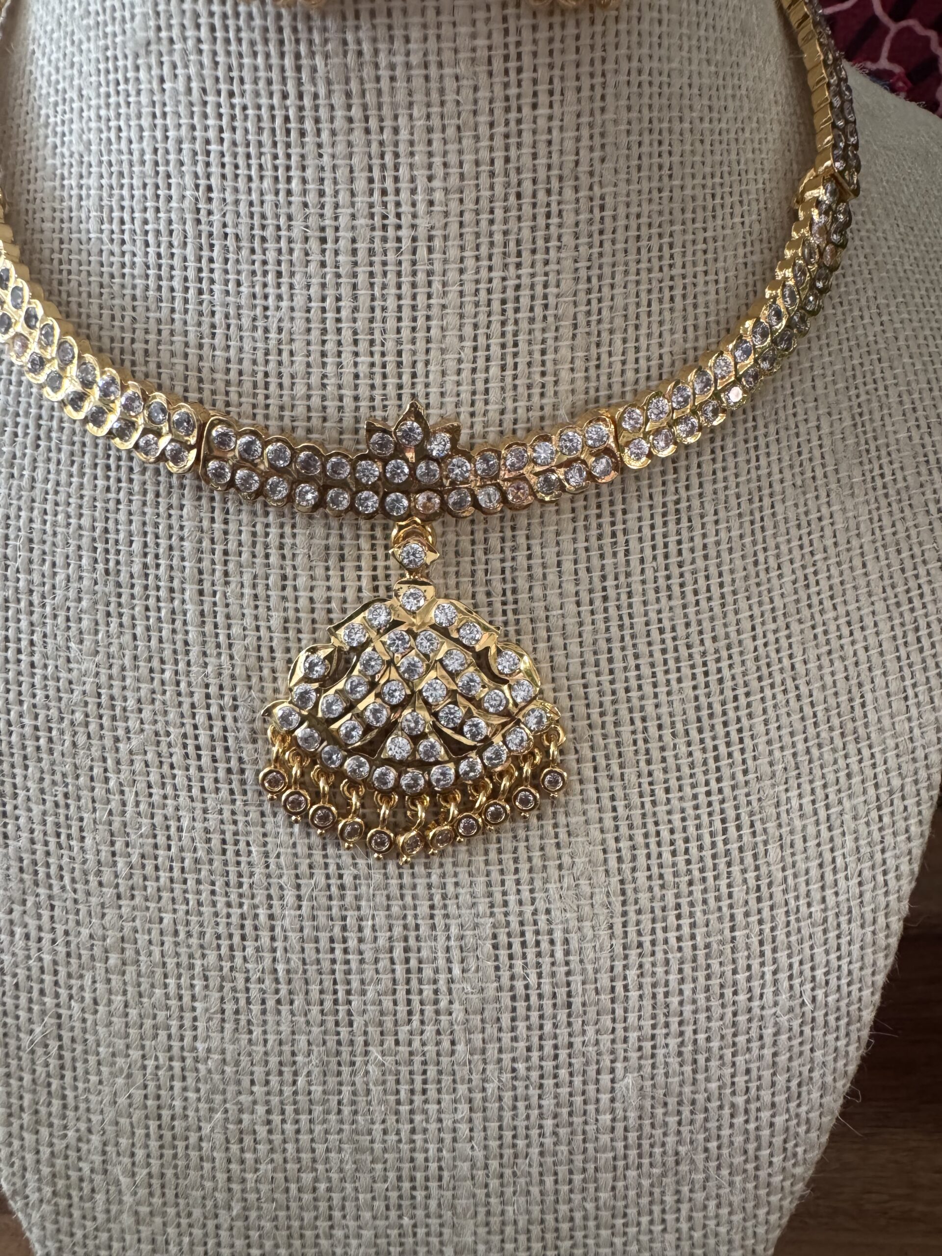 Gold-toned necklace with a pink and green Kundan pendant and pearl drops.