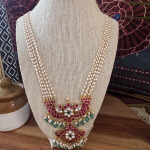Four-strand seed pearl necklace with a large red and green stone Jadau pendant.