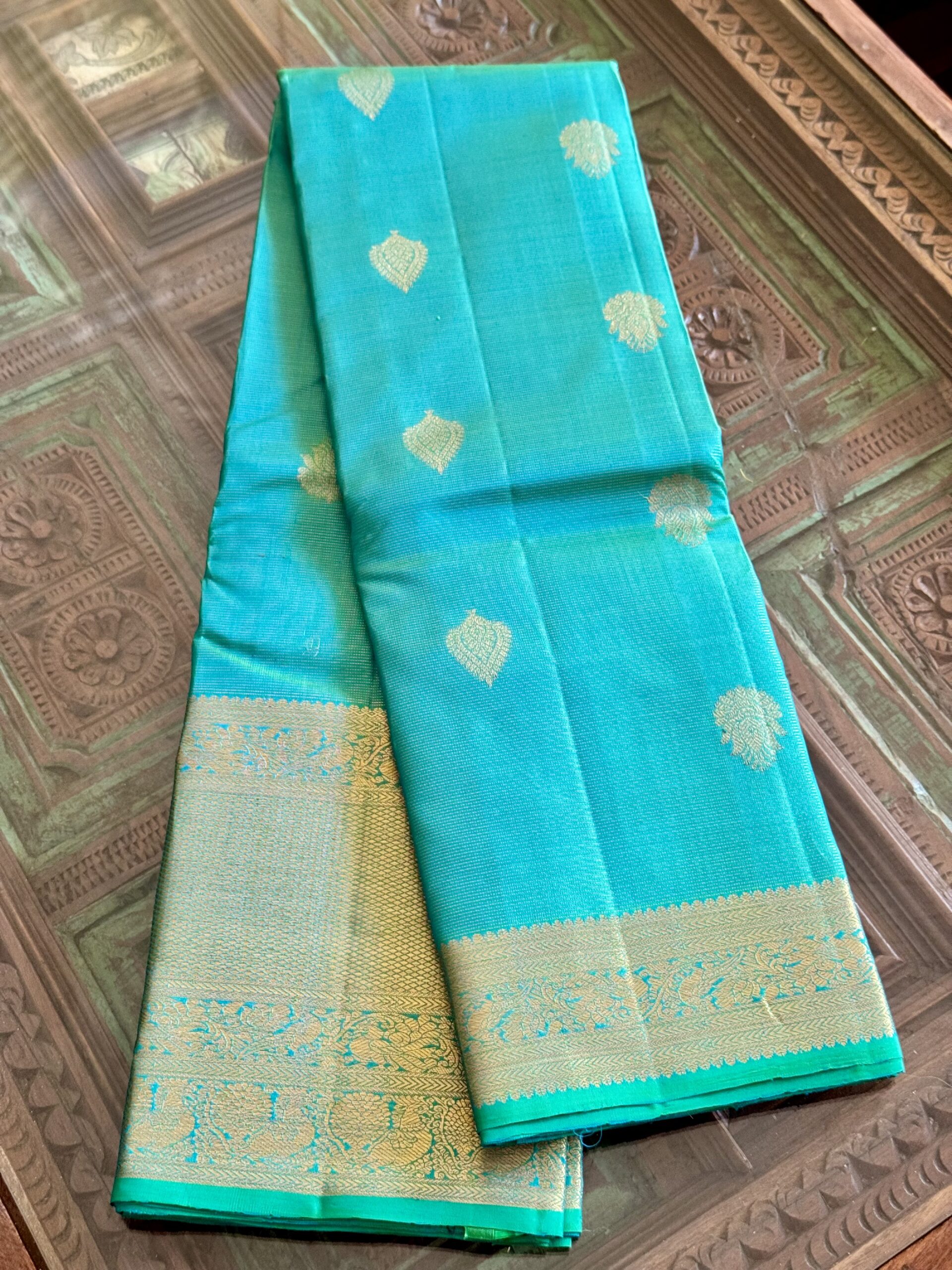 Iniya turquoise blue-green shot Kanjivaram silk saree with zari buttas and uneven Annam borders.