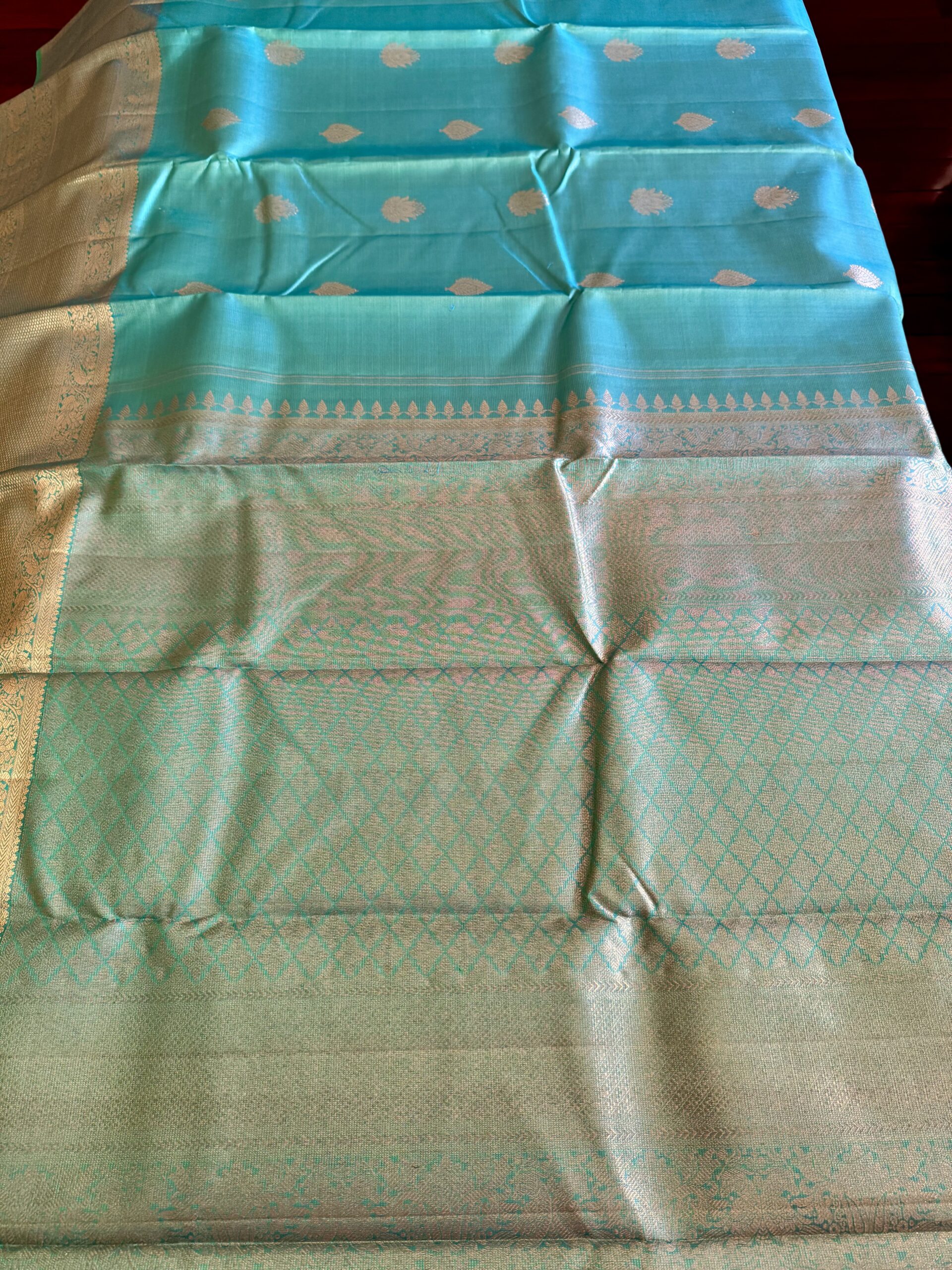 Iniya turquoise blue-green shot Kanjivaram silk saree with zari buttas and uneven Annam borders.