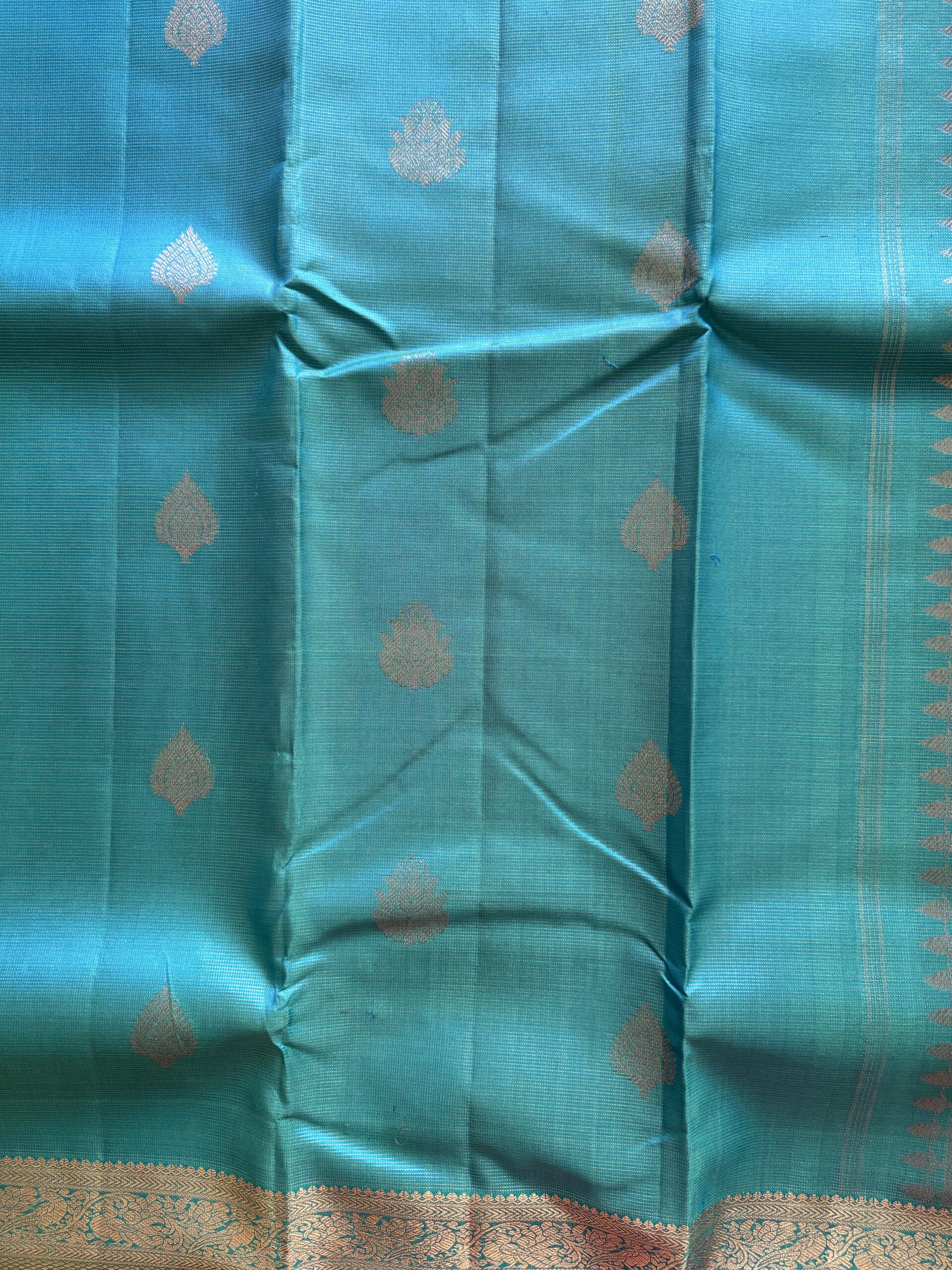 Iniya turquoise blue-green shot Kanjivaram silk saree with zari buttas and uneven Annam borders.