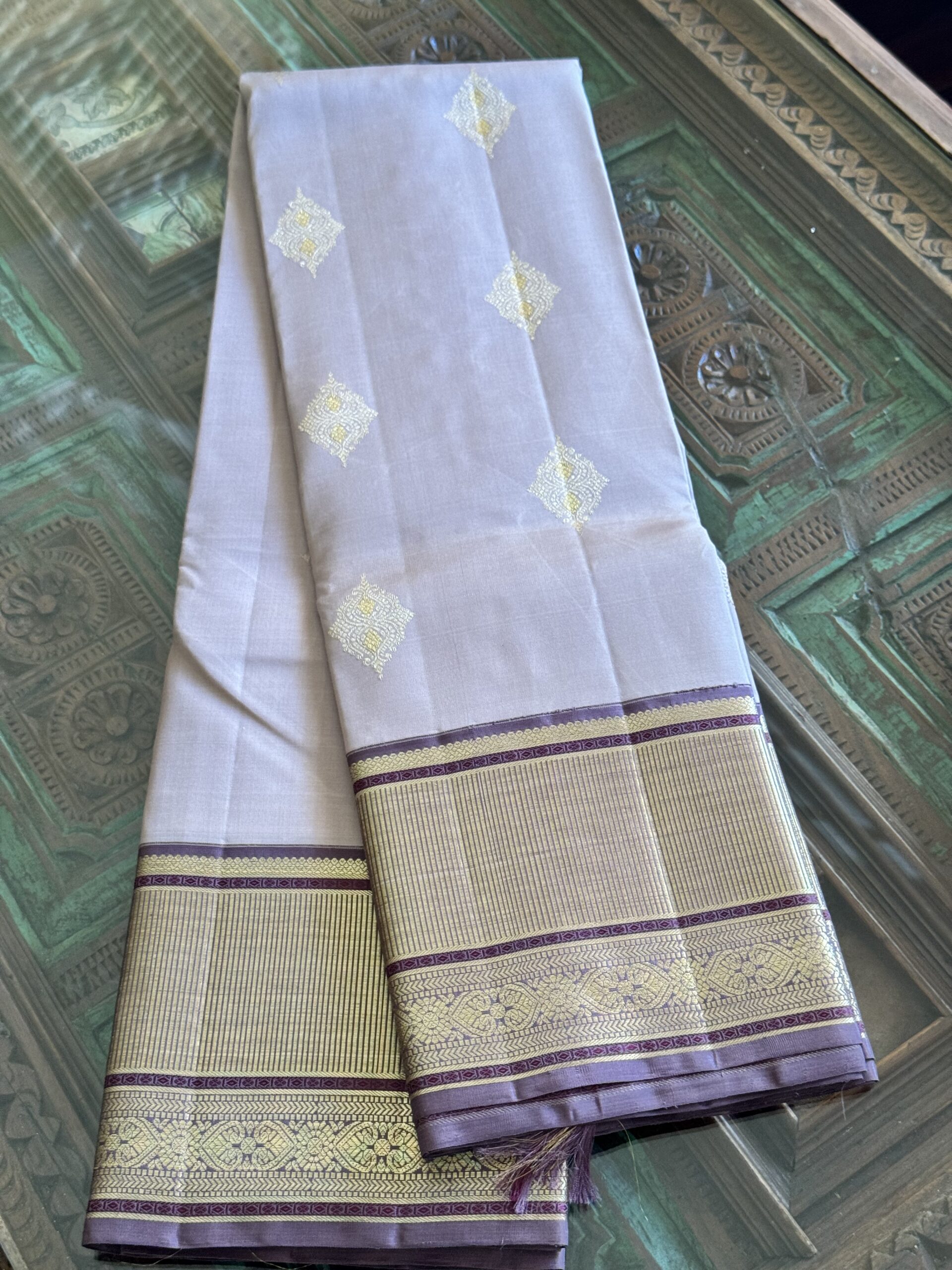 Shop Inaya at Tari by Gayatri. This lavender beige shot Kanjivaram silk saree features 2g zari motifs and a lavender brown selvage.