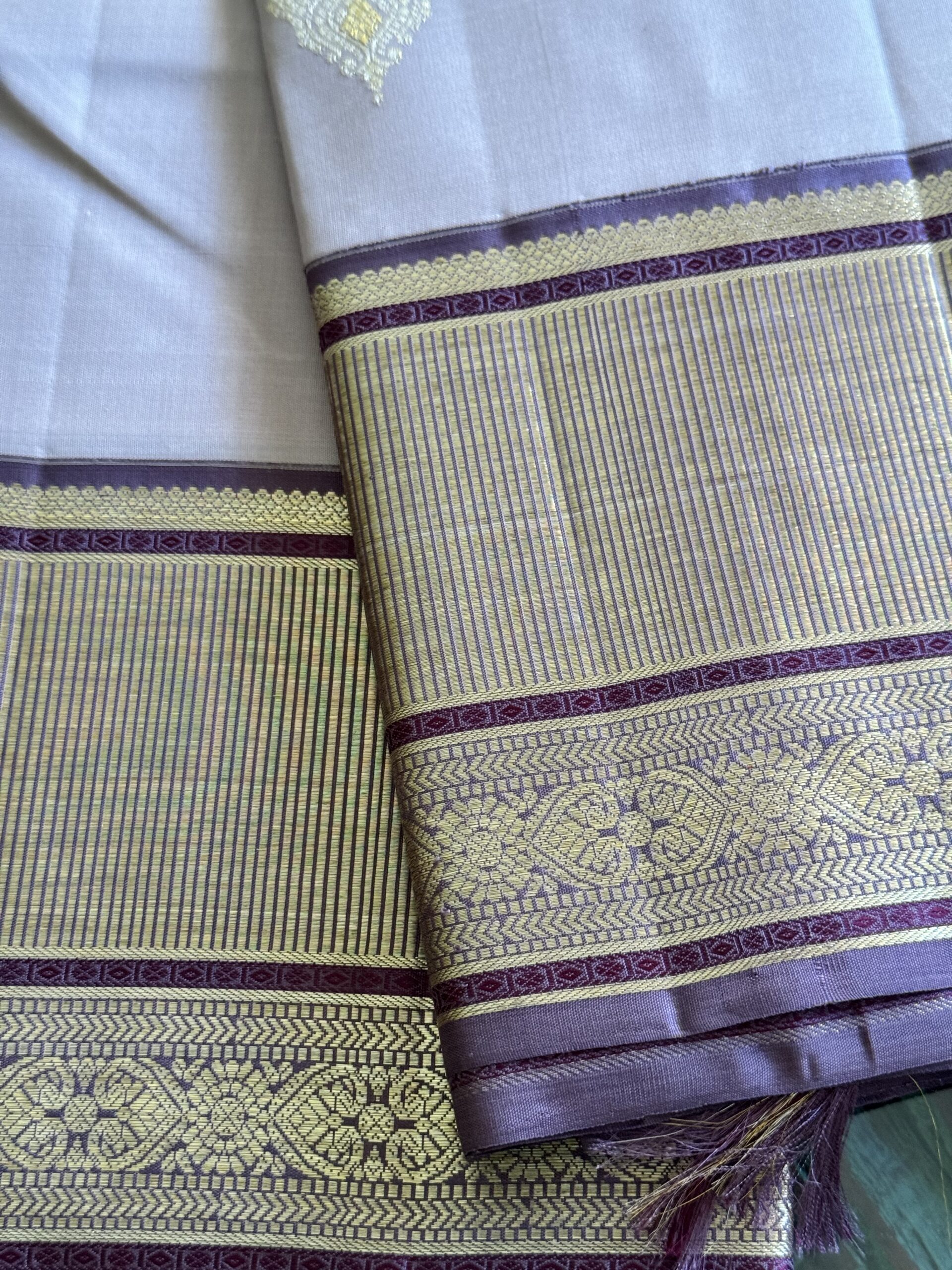 Shop Inaya at Tari by Gayatri. This lavender beige shot Kanjivaram silk saree features 2g zari motifs and a lavender brown selvage.