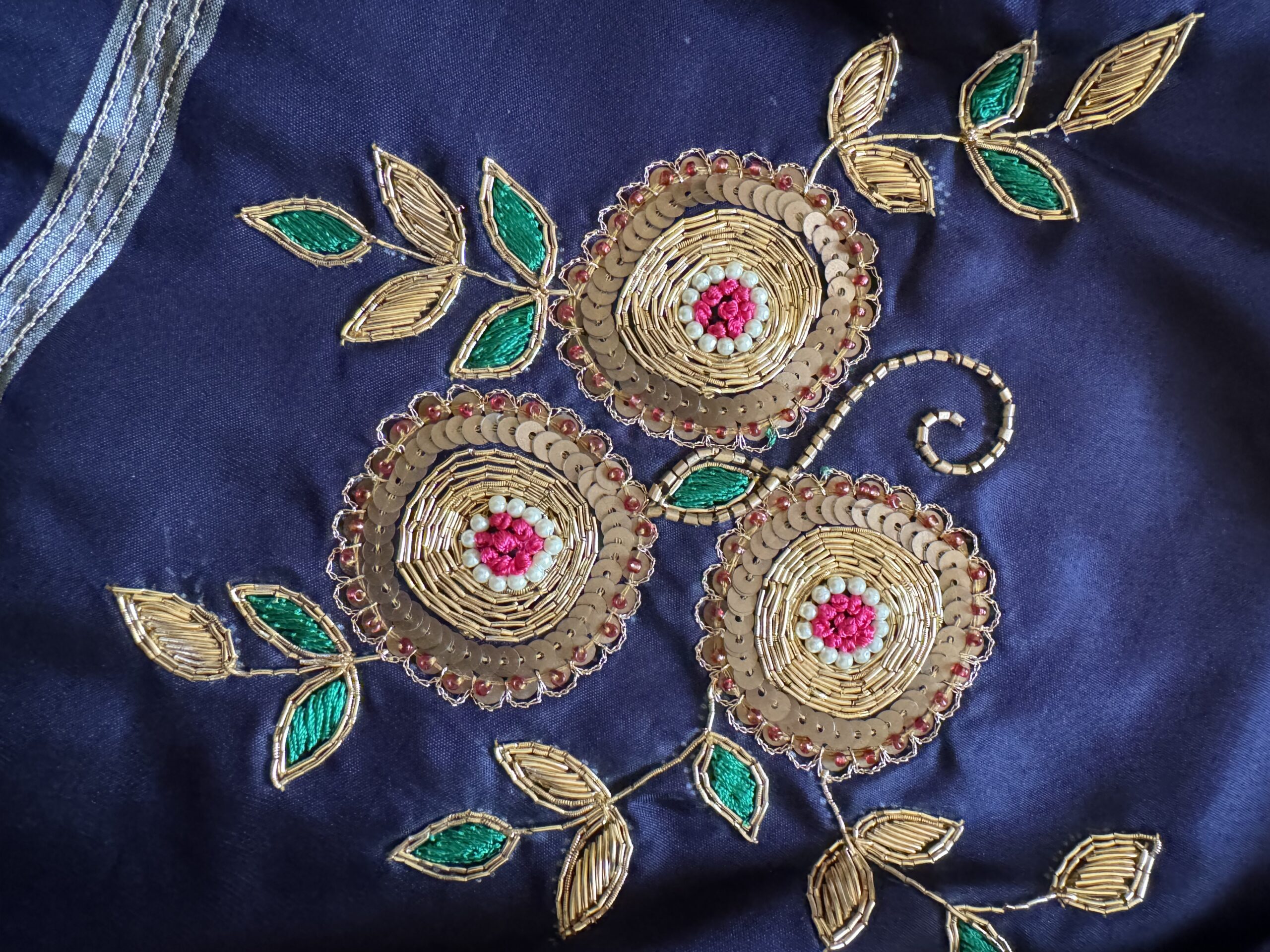 Close-up of hand-embroidered gold zari floral cluster on Indranila midnight blue pure silk saree — circular blooms with pink centres and emerald green leaves — Tari by Gayatri