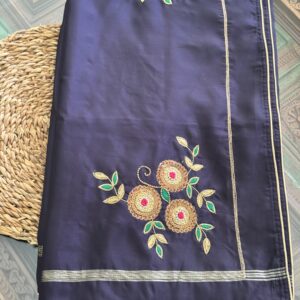 Indranila midnight navy pure silk saree folded, showing scattered hand-embroidered gold zari floral sprigs and slim gold border — Tari by Gayatri