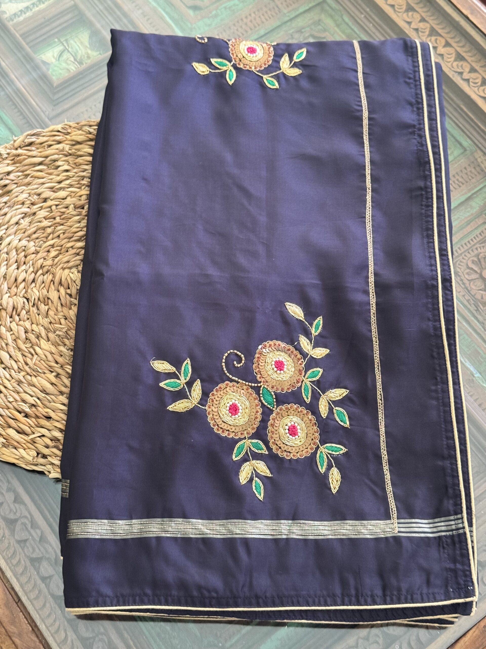 Indranila midnight navy pure silk saree folded, showing scattered hand-embroidered gold zari floral sprigs and slim gold border — Tari by Gayatri