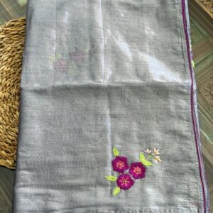 Shubhra silver-grey handwoven tissue silk saree folded, showing scattered hand-embroidered magenta floral sprigs with lime green leaves and fuchsia piping trim — Tari by Gayatri