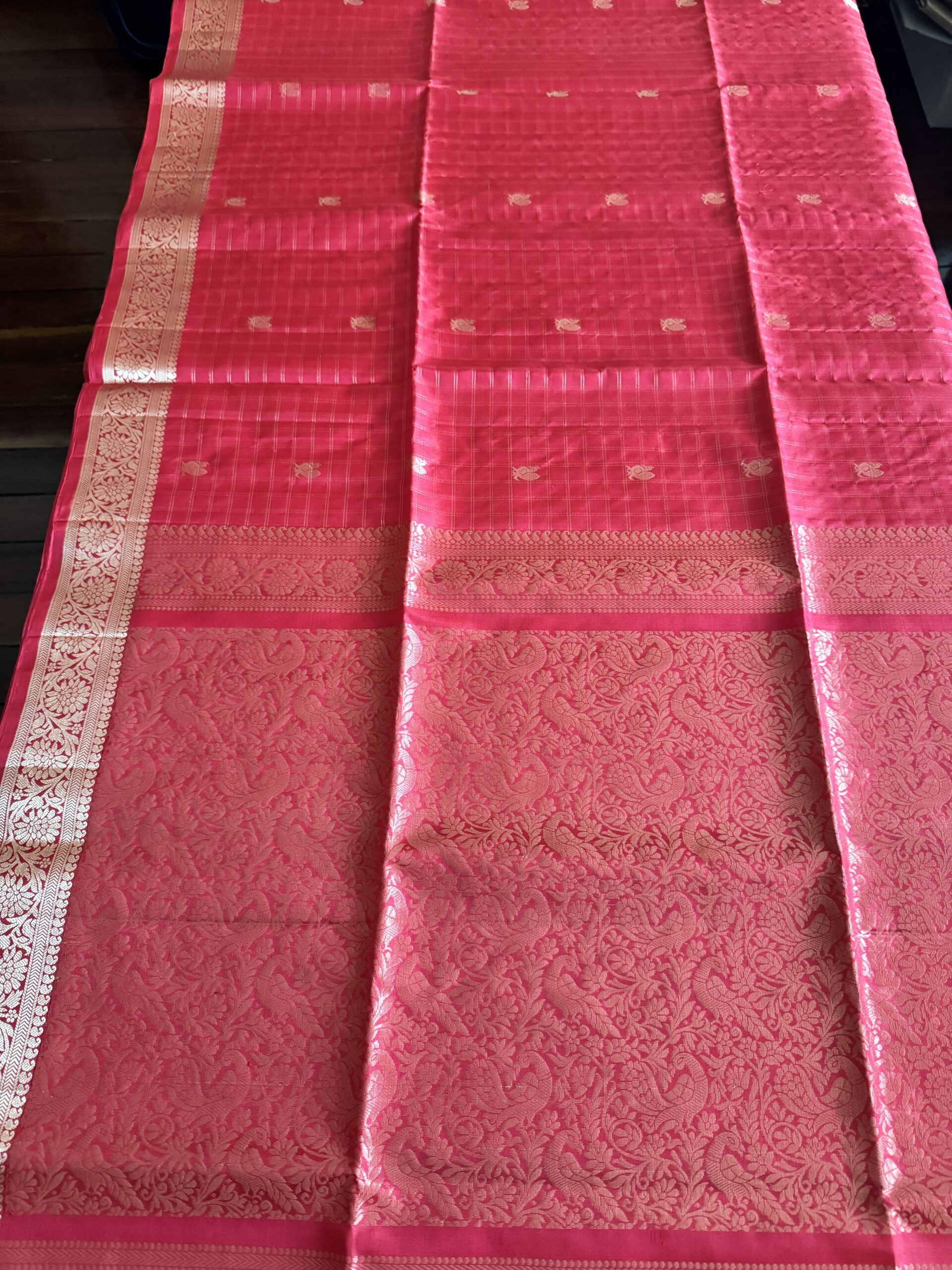 Nandini tomato red soft silk saree with gold zari checks and a peacock pallu with tassels.